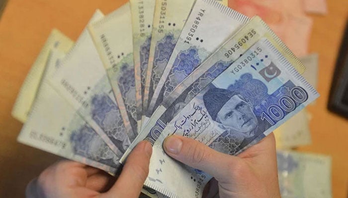 A money changer counts Pakistans currency at a market in Karachi. — AFP/file