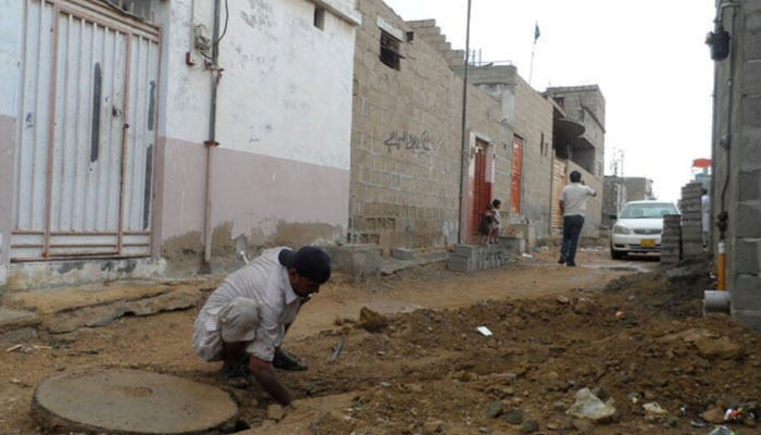 A labourer works to connect a house to a new sewage line in a slum area of Pakistan.  — Reuters/File