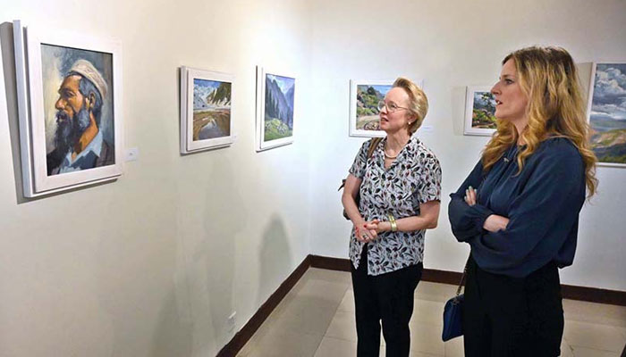 A representational image showing visitors examining art piece on the walls during an exhibition. — APP/File