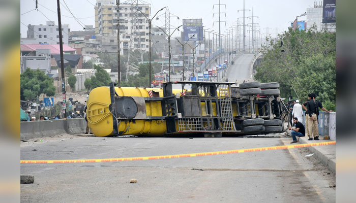 An oil tanker overturned at the Baloch Colony flyover, rescue workers and other officials are seen standing at the spot on July 25, 2024. — APP