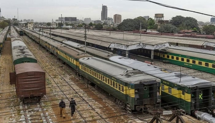 Policemen walk along trains stationed on a deserted platform at Karachi Cantonment railway station. — AFP/file