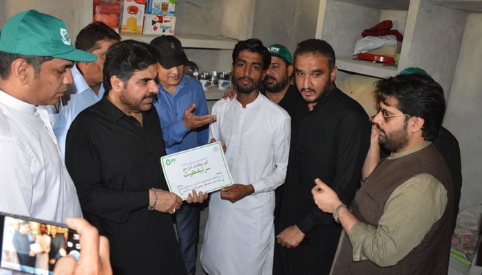 Sindh Minister for Energy, Planning & Development Syed Nasir Hussain Shah hands over ownership document of a house to a flood victom under the Sindh People’s Housing Scheme for Flood Affected People on July 26, 2024. — Facebook/Syed Nasir Hussain Shah