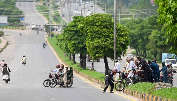 Commuters change routes as police block a street ahead of the Jamaat-e-Islami (JI) party protest against inflation, in Islamabad on July 26, 2024. — AFP