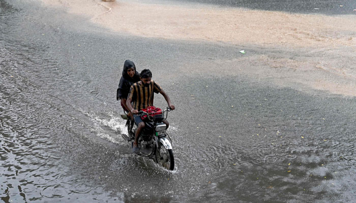 People wade through a flooded street amid heavy rainfall in Lahore on July 28, 2024. — AFP