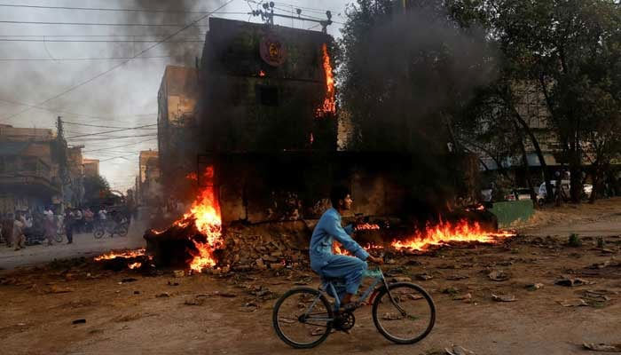 A boy rides past a paramilitary check post, that was set ablaze by the supporters of PTI founder Imran Khan, during a protest against his arrest, in Karachi, on May 9, 2023. — Reuters