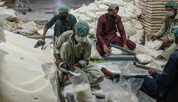 A representational image showing workers preparing sugar bags at a warehouse in Islamabad. — AFP/File