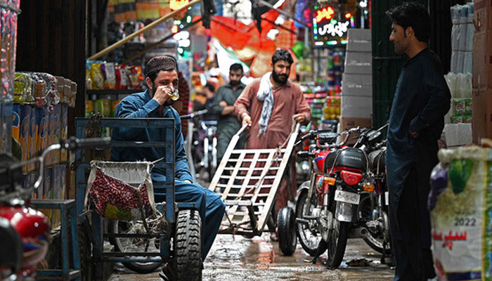 A trader drinks tea along an alley in a market in Rawalpindi on June 1, 2023. — AFP