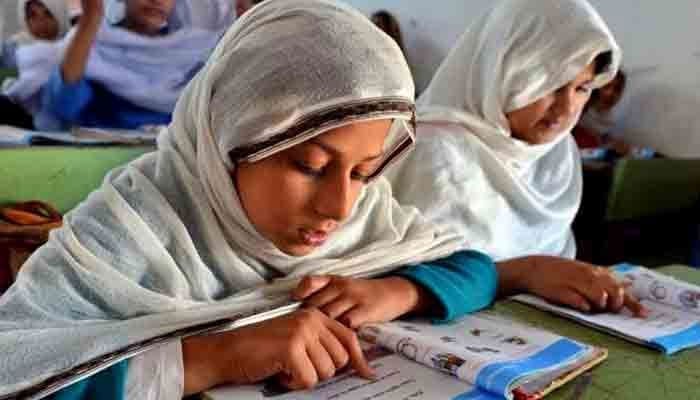 In this image, students reading a book in a classroom. — AFP/File