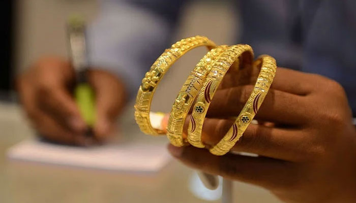 An undated image of a goldsmith showing gold bangles to a customer. — AFP/File