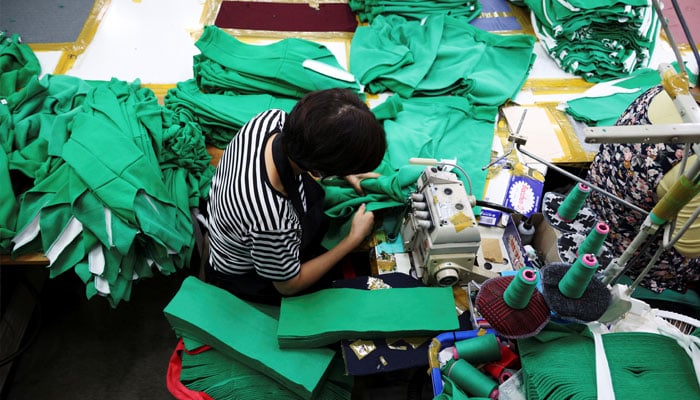 A woman works on tracksuits at a clothing factory in Seoul, South Korea on October 21, 2021. — Reuters