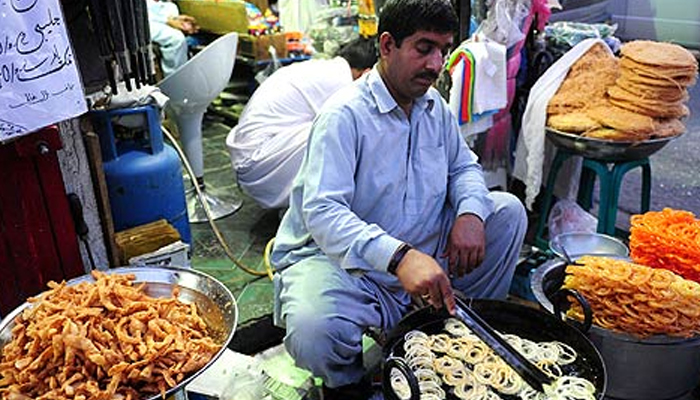 A Pakistani sweets maker, prepares jalebi, a popular dessert, at his roadside stall. — AFP/file