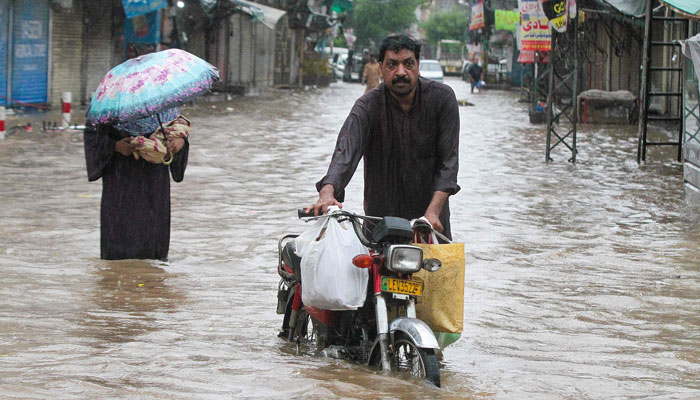 A man wades through a flooded street during heavy rainfall in Lahore on August 1, 2024. — AFP