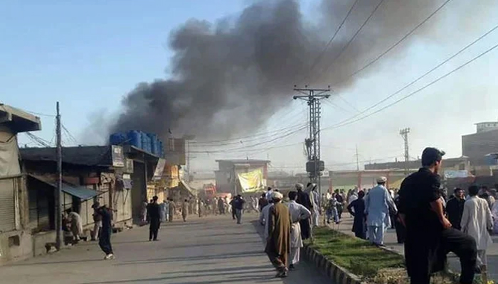 Residents watch clouds of smoke gather on the road after two explosions in a market in Parachinar, the capital of Kurram tribal district. — AFP/File