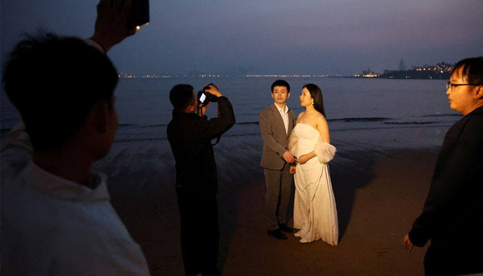 A couple poses for a pre-wedding photoshoot after sunset on a beach in Qingdao, Shandong province, China April 21, 2024. — Reuters