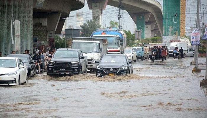 Commuters pass through accumulated rainwater in Karachi. — APP/file