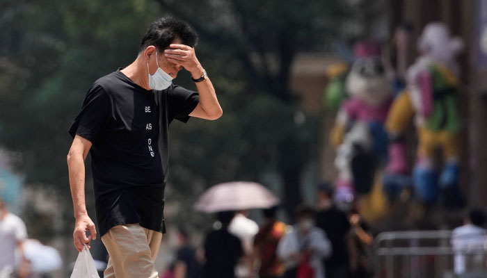 A man wearing face mask reacts on a street amid a heatwave warning in Shanghai, China on July 13, 2022. — Reuters