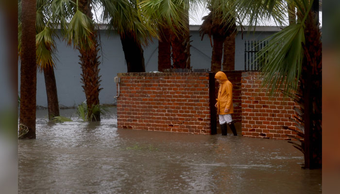 A person walks through a flooded street caused by the rain and storm surge from Hurricane Debby in Cedar Key, Florida on August 05, 2024. — AFP