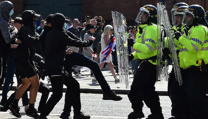 Police officers face protesters outside the Liver Building in Liverpool during a demonstration held in reaction to the fatal stabbings in Southport, UK. — AFP/File