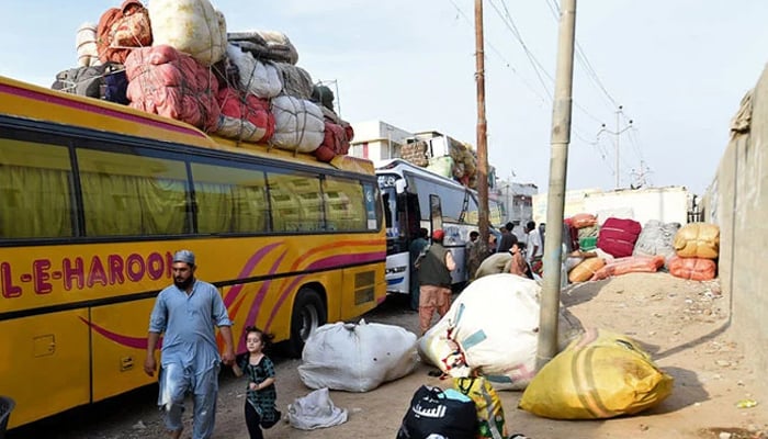 People load their belongings onto a bus at the Karachi bus terminal in Sindh on October 27, 2023. — AFP