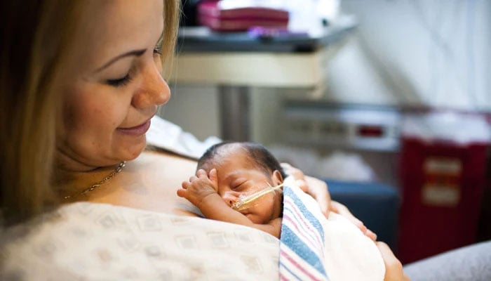 This representational image shows a premature baby lying in her mothers hands. — X/chc/File