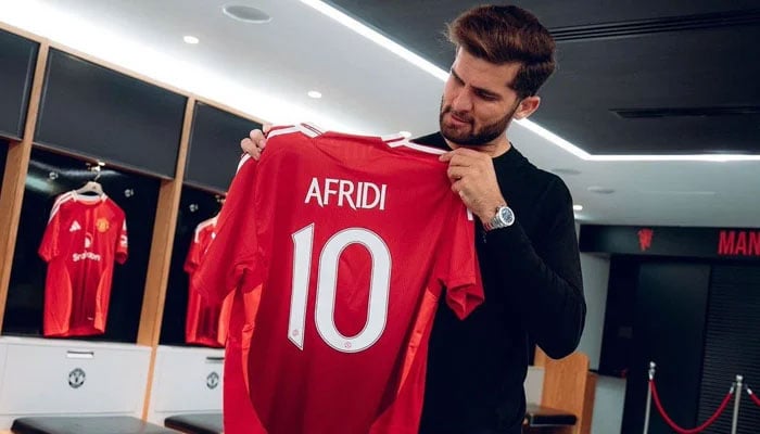 Pakistans cricket star Shaheen Shah Afridi poses with a jersey of Manchester United. — photo provided by reporters