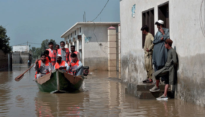 Volunteer rescue officials patrol on a boat at a residential area submerged in floodwater in Nowshera of Khyber Pakhtunkhwa on August 29, 2022. — AFP