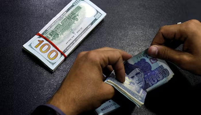 A currency trader counts Pakistani Rupee notes as he prepares an exchange of US dollars in Islamabad on December 11, 2017. — Reuters