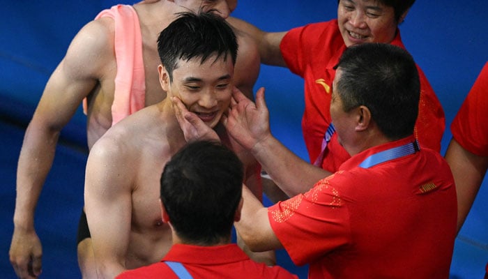 Chinas Cao Yuan (L) is congratulated by his coaches after winning the gold medal in the mens 10m platform diving final during the Paris 2024 Olympic Games in Paris on August 10, 2024. — AFP