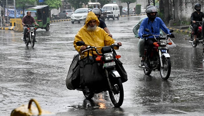 Motorcyclist covering himself with plastic sheet to get protected from rain on August 10, 2024. — APP