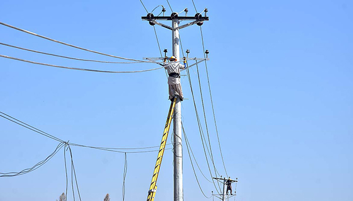 Workers seen on an electric pole in Islamabad, on October 26, 2023. — APP