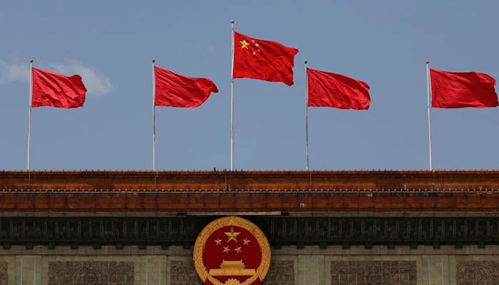 A Chinese flag flutters above the Chinese national emblem at the Great Hall of the People after the opening session of the National Peoples Congress (NPC) in Beijing, China. — Reuters/File