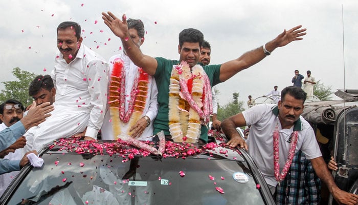 Arshad Nadeem (C), Pakistans javelin gold medallist at the Paris 2024 Olympic Games, waves to fans upon his arrival at his hometown in Mian Channu on August 11, 2024. — AFP