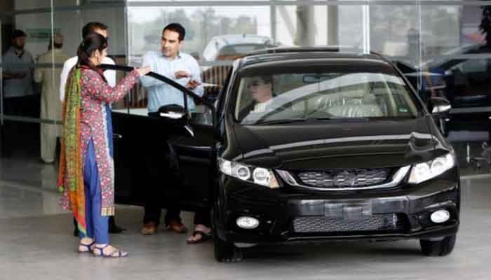 A representational image showing a customer speaking with salespeople at a car dealership in Rawalpindi.— Reuters/File