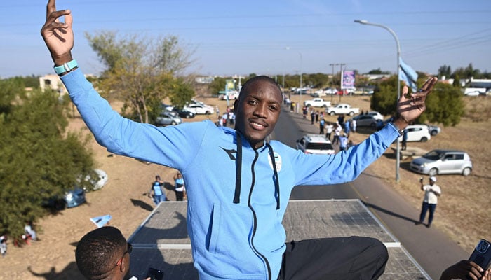 Olympic gold medallist, Botswanas Letsile Tebogo, who won the mens 200m athletics event during the Paris 2024 Olympic Games, gestures as he travels on an open bus during a welcoming ceremony in Gaborone on 13 August 2024. — AFP