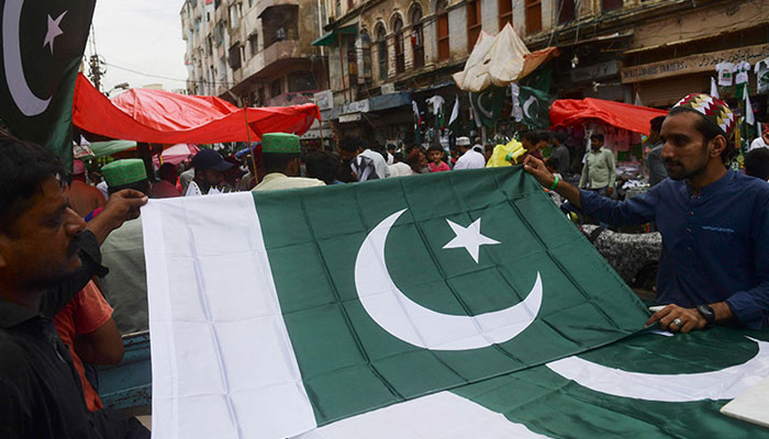 People buy national flags at a market ahead of Pakistans 75th Independence Day in Karachi on August 12, 2022. — AFP