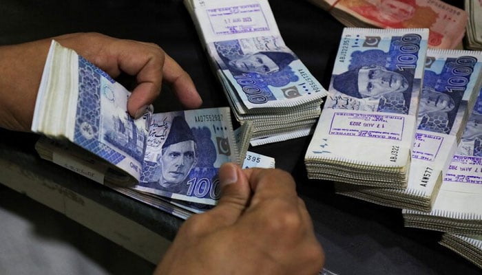 An employee counts Pakistani rupee notes at a bank in Peshawar on August 22, 2023. — Reuters