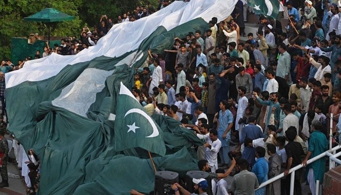 A representational image showing people carrying a national flag at the Pakistan-India Wagah border post on August 13, 2023. — AFP