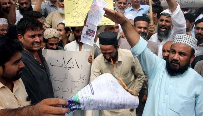 Citizens burn electricity bills as they are holding protest demonstration against the highly inflated electricity bills, held in Peshawar on Saturday, August 26, 2023. — PPI