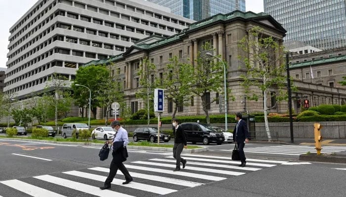 Pedestrians walk in front of the Bank of Japan head office building in Tokyo on April 27, 2022. — AFP