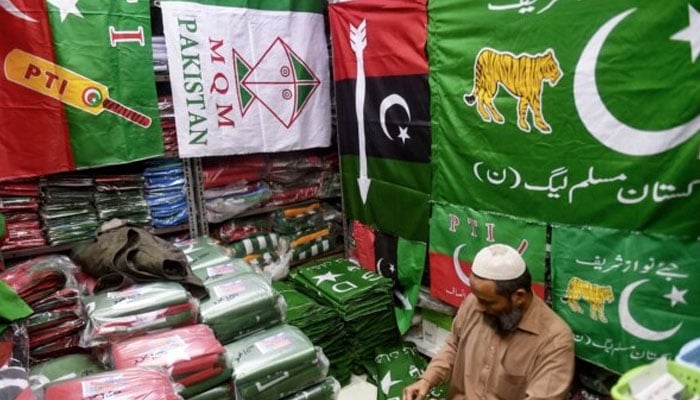 A shopkeeper arranges flags of political parties at his shop in Karachi on Jan. 3, 2024. — AFP