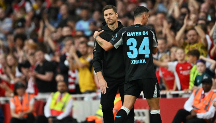 Bayer Leverkusens Swiss midfielder Granit Xhaka (R) hugs Bayer Leverkusens Spanish head coach Xabi Alonso after being substituted during the pre-season friendly football match between Arsenal and Bayer 04 Leverkusen in London on August 7, 2024. — AFP