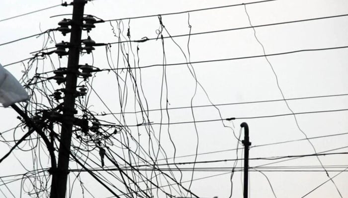 Due to the high cost of electricity for the public in Lahore, people have put more than 10 cords on the electricity pole. — APP/file