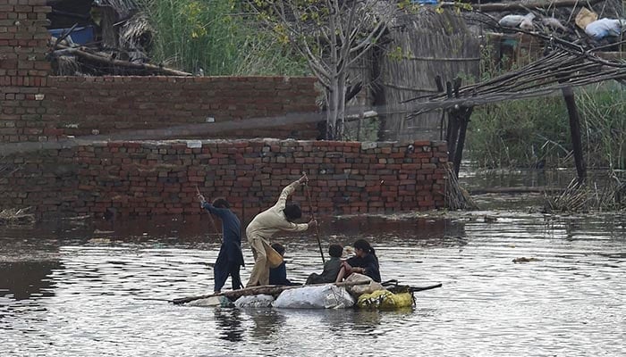 Children use a raft to make their way in a flooded area after heavy monsoon rains on the outskirts of Sukkur, Sindh on August 27, 2022. — AFP