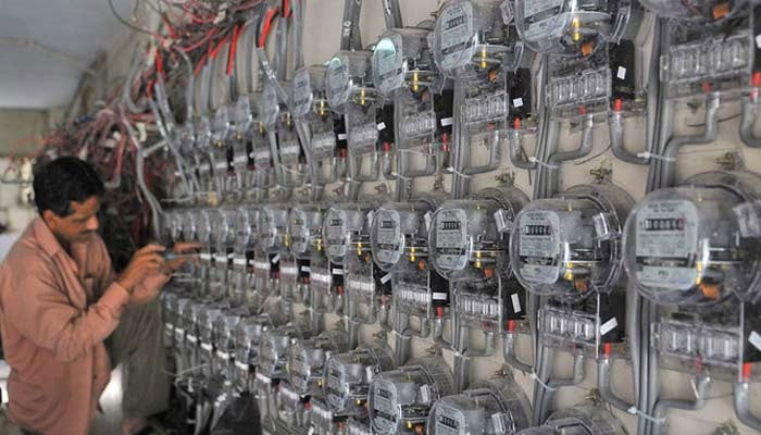 A technician fixes new electricity meters at a residential building in Karachi, Pakistan, on May 13, 2010. — AFP