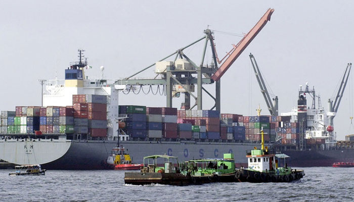 Vessels pass by a container ships being loaded with cargo at Karachi port. — AFP/File