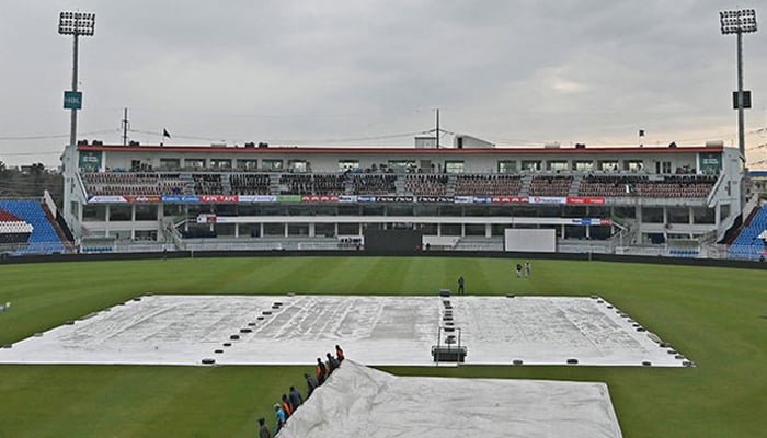 Ground staff members cover the field with a plastic sheet following rain showers at the Rawalpindi Cricket Stadium. — AFP/File