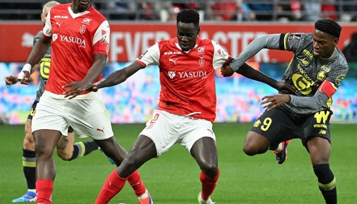 Reims Ivorian forward Oumar Diakite (C) fights for the ball with Lilles Canadian forward Jonathan David during the French L1 football match between Stade de Reims and Lille LOSC at the Stade Auguste-Delaune in Reims, northern France, on August 17, 2024. — AFP