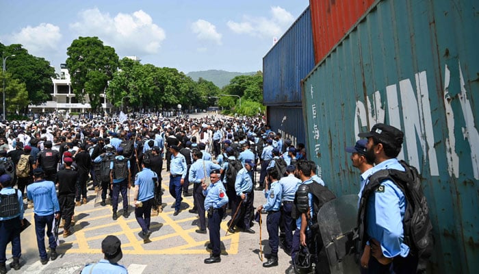 Security personnel stand guard as people gather near the capital´s red zone, for a protest in Islamabad on August 22, 2024. — AFP