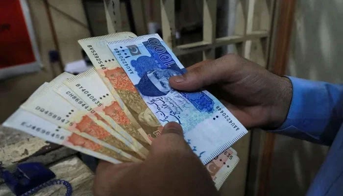 A man counts Pakistani rupee notes at a currency exchange shop in Peshawar on September 12, 2023. — Reuters