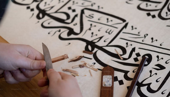 A representational image showing a person carving a pencil for use in calligraphy. — Unsplash/File